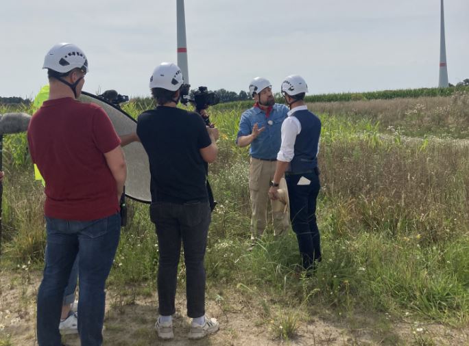 Im Vordergrund steht ein Fernsehteam des ZDF-Fernsehgarten on Tour, das die zwei Protagonisten vor der Kamera beobachtet.